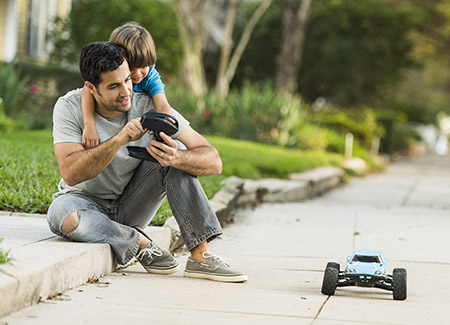 lifestyle image of father and son playing with a RC car